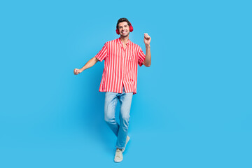 Full size photo of optimistic man dressed striped shirt denim pants listen playlist in headphones...
