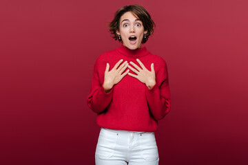 Portrait of shocked amazed woman gasps from wonder, holds hands on her chest