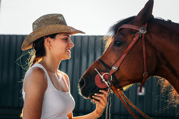 Woman taking care of his brown horse in an equestrian center