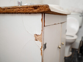 Old worn out cabinet with British style separate tabs for water and sink made of chip wood and in...