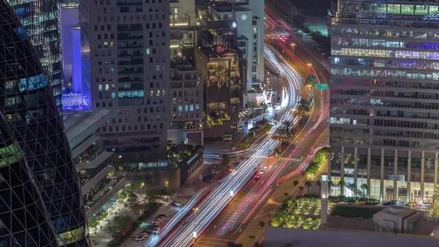 Aerial view of traffic on Al Saada street in financial district day to night transition timelapse in Dubai, UAE. Illuminated skyscrapers and glowing windows in office towers from above.