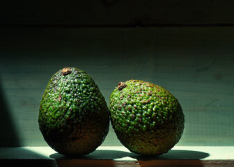 Image of ripe organic grown avocado fruit in a wooden box in bright sunlight with copyspace.