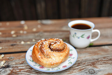 Cup of coffee and plate with cinnamon roll
