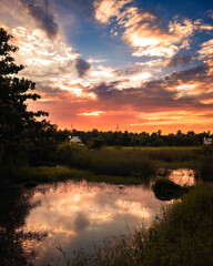 Beautiful sunset, colorful dusk evening sky reflection in lake behind the bayou of cypress swamp in California. Landscape western country nature photography of afternoon twilight on river in Florida.
