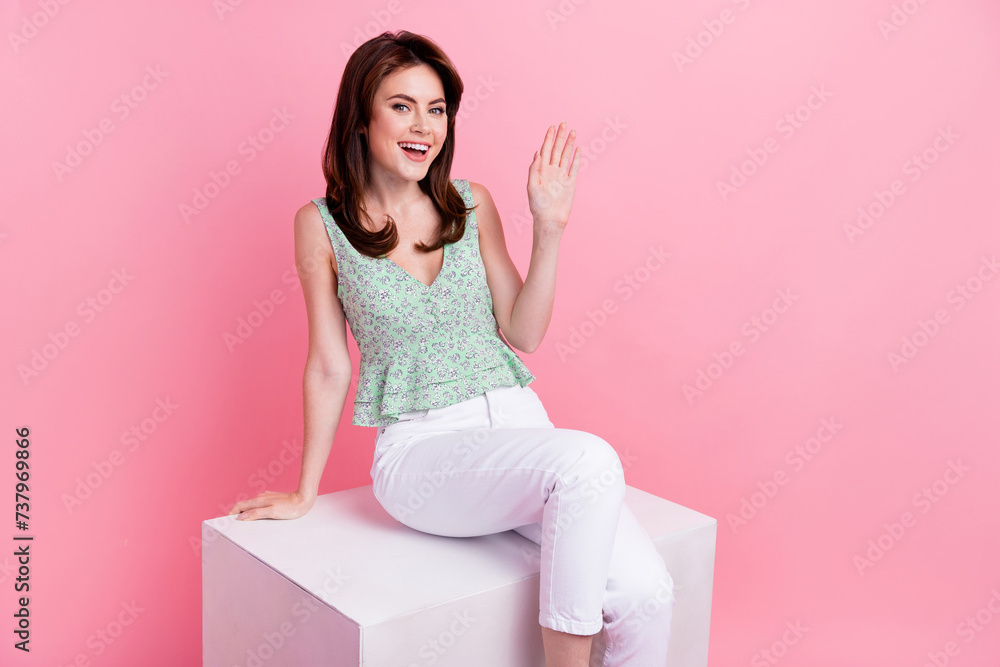 Poster Photo of glad optimistic girl wearing fashionable outfit waving arm palm saying hello isolated on pink color background