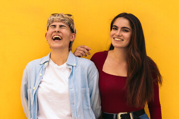 two teenager girls laughing on a yellow background