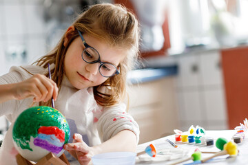 Little girl painting globe or ball with colors. School child making earth globe for school project....