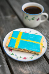 Cup of coffee and cake colored with Swedish flag 
