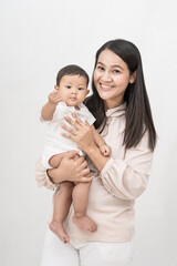 Beautiful mom holding baby girl and laughing very happy on isolated background.