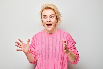 Portrait blond young woman happy face smiling joyfully with raised palms and shocked open mouth...