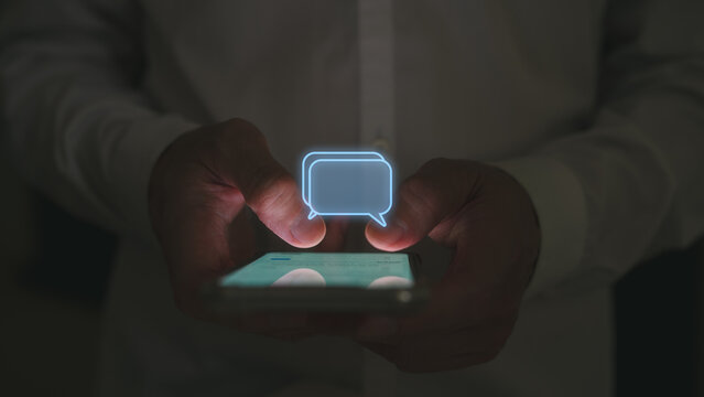 Social media marketing concept. low light shot Man hand using smartphone typing, chatting conversation in chat box icons pop up