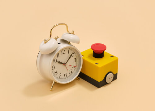 Retro white alarm clock and red start button. Time and work.