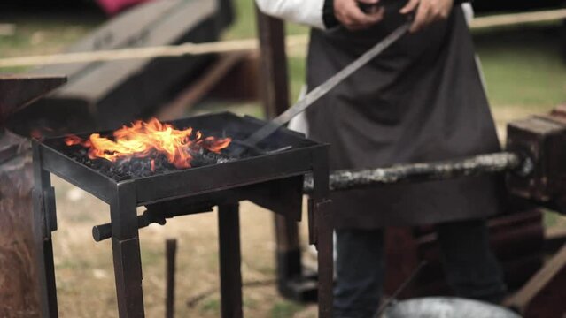 A blacksmith forges a sword. Middle-earth, medieval, craft, metal, metal roasting, fire, charcoal, festival, geek culture, cosplay.