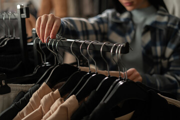 Woman choosing new sweater in Clothes Shop. Fashion store concept