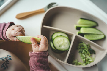 A child tries a cucumber using the blw, method, first feeding