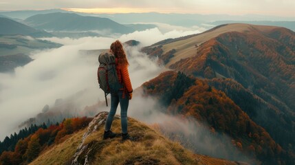Fototapeta premium Girl with backpack on mountain peak looking in beautiful mountain valley in fog at sunset in autumn.