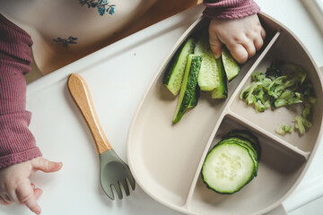 A child tries a cucumber using the blw, method, first feeding