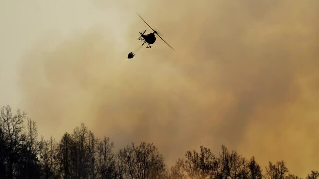 Fire fighting helicopter dropping water on  wildfire