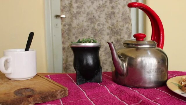 Tradiciones orientales en sudamerica del t&eacute; verde, con la mesa puesta con pocillos, la tetera y la hierba de t&eacute; verde servida por el hombre, acompa&ntilde;ada de pan tostado en el plato.