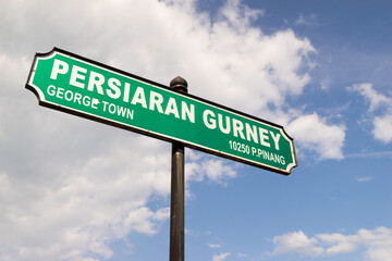 Gurney Drive street sign in George Town, Penang, Malaysia with blue sky and white clouds as background.