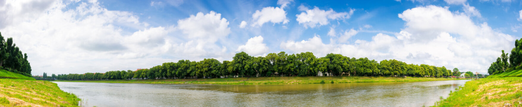 panorama of the river uzh in summer. longest linden alley in europe beneath a gorgeous sky with clouds on a sunny day. popular tourist attraction of uzhhorod in ukraine
