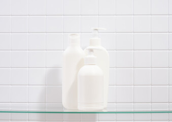 White dispensers with gels for cleansing and skin care on a white tile background. Skin care procedure.