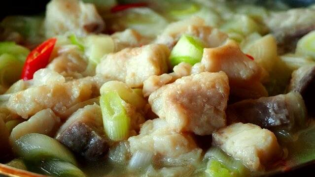 Frying Japanese spring onions with chopped fishes in pan, in door Chiangmai Thailand.