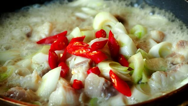 Frying Japanese spring onions with chopped fishes in pan, in door Chiangmai Thailand.