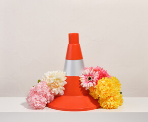 Orange bright construction cone and colorful flowers. Instruments and equipment.