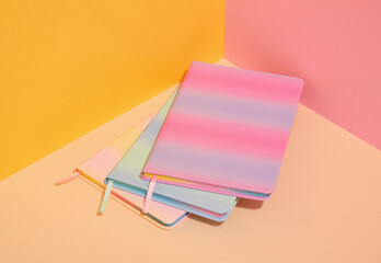 Three colorful, brightly colored notebooks on the table. Variety of school supplies.