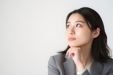 考えているの日本人の女性会社員のポートレート（白背景・サラリーマン・スーツ・若手・新人・新入社員） - obrazy, fototapety, plakaty