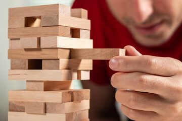 Close up hand man take one block on The tower from wooden blocks