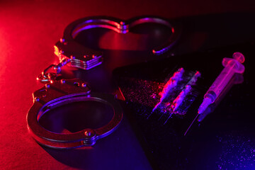 Drug smuggling and trafficking and handcuffs and bags of cocaine on black background.