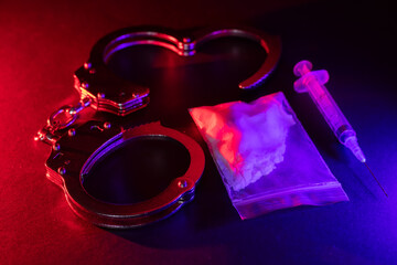 Drug smuggling and trafficking and handcuffs and bags of cocaine on black background.