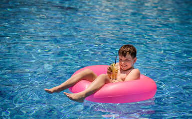  Child is smiling and drinking cocktail in the swimming pool..