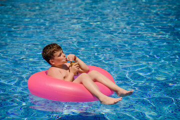  Child is smiling and drinking cocktail in the swimming pool..