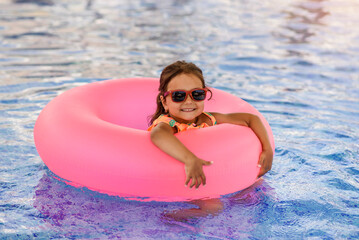 Little girl kid, is swimming with an inflatable circle in the swimming pool.