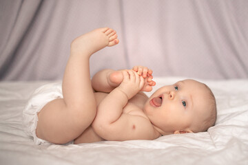baby pulls his foot into his mouth, BCG vaccination mark on his arm, baby 7 months portrait