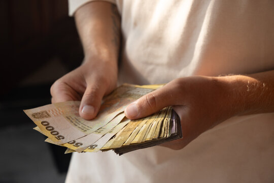 Sri Lankan rupees in mans hand counting of different denominations. Rupee is currency of Sri Lanka. Close up.