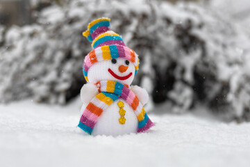 A fabric snowman in hat, scarf, in winter forest. Concept of winter, snow and childhood.