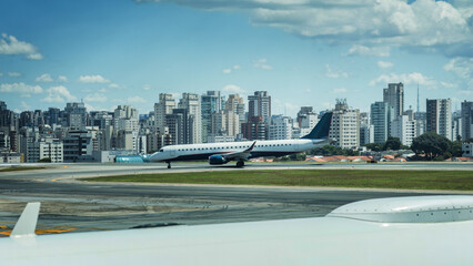 Commercial Airplane Prepares for Takeoff at Congonhas Airport on a Sunny Day with Sao Paulo, Brazil skyline in the background