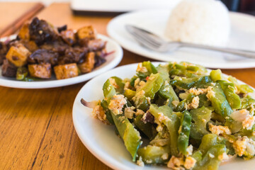 Ginisang ampalaya with egg, known as Sauteed Bitter Melon, served with tokwa baboy and rice at a Filipino restaurant.