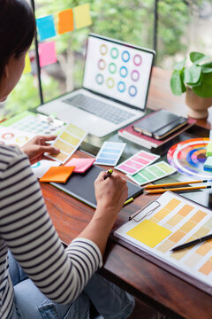Creative graphic designer holding color swatch to choosing color and working to designing on tablet