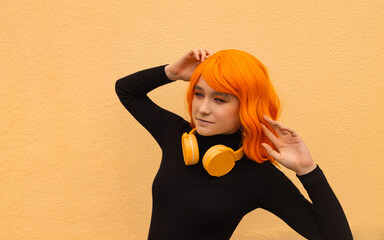 Girl dancer with creative orange hair and hairstyle and headphones. Lifestyle photo. Cosplay on an anime character. - 738046449