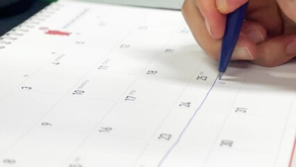 the hand of a person who marks his vacation on the calendar
