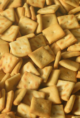 Background texture of small edible squares baked from dough and sprinkled with salt. A lot of salt cracker