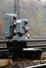 Photo of a fragment of a railway track with a small traffic light in rainy weather