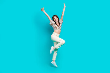 Fototapeta na wymiar Full length photo of funky excited lady dressed flower print top rising hands arms jumping high isolated turquoise color background