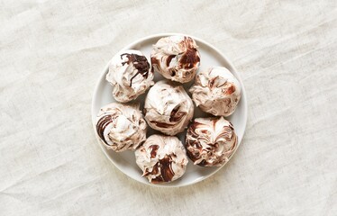 Chocolate meringue cookies on plate over light background