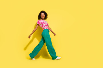 Photo of cool positive young person good mood walking empty space isolated on yellow color...
